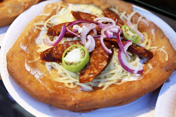 Freshly baked traditional hungarian langos langosch langosh with cheese and spicy sausage for sale