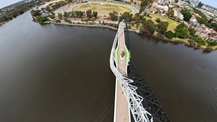 An aerial view captures a striking arched Matagarup Bridge spanning calm Swan river with the modern Perth cityscape, Western Australia. - Powered by Adobe
