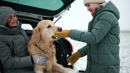Happy Mother And Daughter Play With Golden Retriever Dog In A Car Trunk At A Winter Road Rest Stop