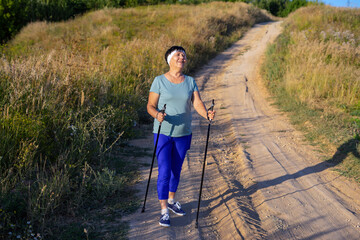Senior woman nordic walking in the countryside