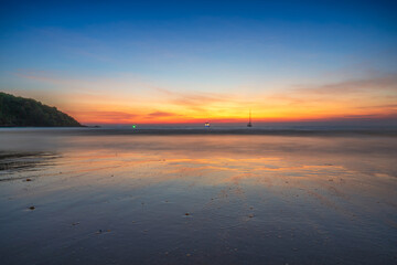 Beautiful tropical beach at sunset with golden light reflecting on the wet sand under a vibrant twilight sky