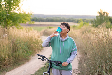 Senior woman on a bike on the street in countryside summer