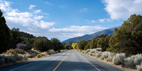 Scenic road through mountain landscape in autumn with blue sky and clouds