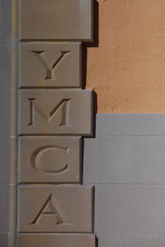 Vintage Etched Stone Letters Displaying YMCA on a Building Facade.  Editorial use only January 9, 2026 	9. Petersburg, FL USA. Decorative stone carving showcasing the letters YMCA on a wall, symbol