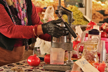eine Frau presst aus Granat&auml;pfeln Saft mit einer Saftpresse