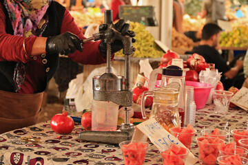 eine Frau presst aus Granat&auml;pfeln Saft mit einer Saftpresse