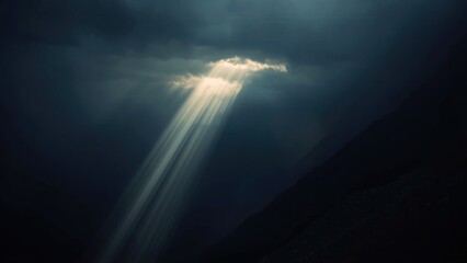 A dramatic mountain landscape with sunbeams piercing through dark clouds