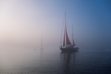 Red Sailboat Emerging from Thick Arctic Fog in Greenland © Michel