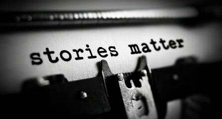 Black and white close up of the phrase stories matter typed onto paper using a vintage mechanical typewriter emphasizing literary importance and communication.