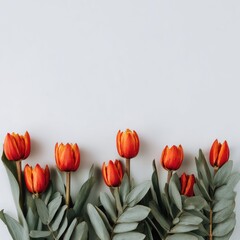 Vibrant orange tulips & leafy branches arranged against a neutral background