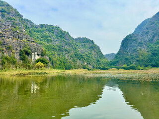 The emerald Ngo Dong river winding through rolling limestone mountain ranges in the peaceful land of Ninh Binh province