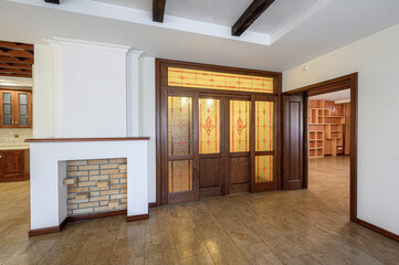 Obraz premium Spacious room with a white fireplace featuring brick interior, stained-glass wooden doors, tiled flooring, exposed wooden ceiling beams, open doorways to a shelved area