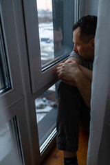 Desperate man in front of a window. Depression and anxiety are two of the main illnesses that...