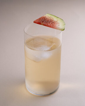 Minimalist Light-Colored Drink with Watermelon Slice and Ice Cube on Light Background