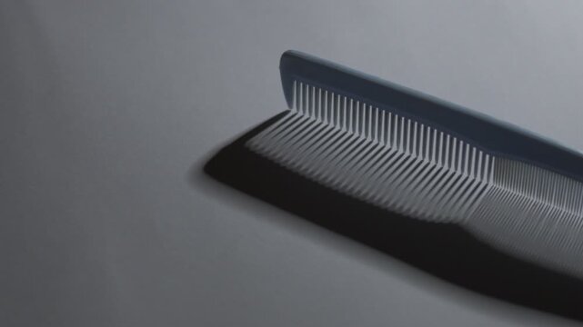 smooth camera movement from left to right over a stationary blue plastic comb on a minimal background