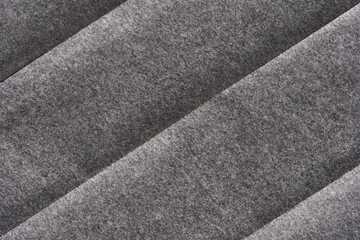 Fototapeta premium Textured grey felt fabric closeup with parallel diagonal patterns creating depth and dimensional effect.