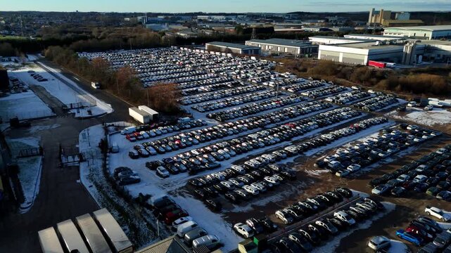 Aerial view of BCA car storage facility showing rows of cars under the winter sun, creating a stark contrast with the light snow, Corby, United Kingdom.