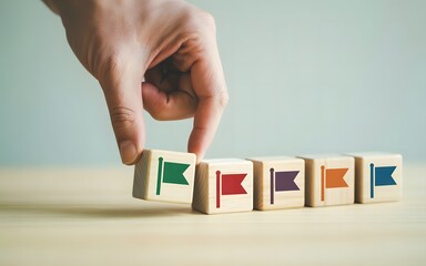 Hand placing first flag block representing goal setting progress milestones strategic planning leadership direction and step by step business success journey