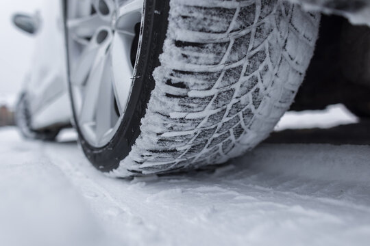 Extreme macro of winter tire tread blocks filled with snow. High-contrast shot showcasing the intricate sipes and rubber texture designed for maximum grip and safety on frozen, icy roads.