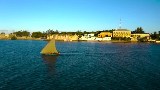 Aerial view of a dhow sailing on the shimmering sea, its sail catching the golden sunset light, creating a stunning contrast, Nampula, Mozambique.