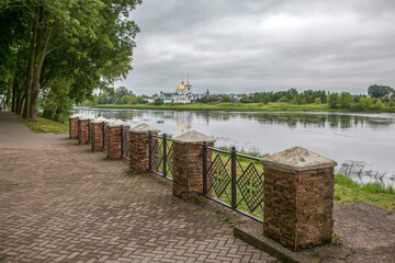 The well-maintained embankment of the Velikaya River with a view of the Spaso-Kazansky Simansky Convent. Ostrov, Pskov Oblast, Russia