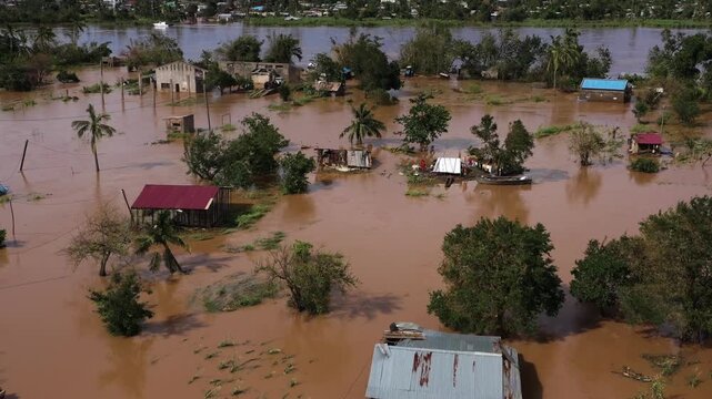 Aerial view of flooded houses and trees amidst the muddy waters, showcasing the devastation and the contrasting colors of nature, Beira, Sofala Province, Mozambique.
