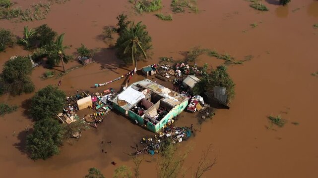 Aerial view of floodwaters engulfing homes and trees, with a palette of brown and green creating a stark contrast, Beira, Sofala Province, Mozambique.