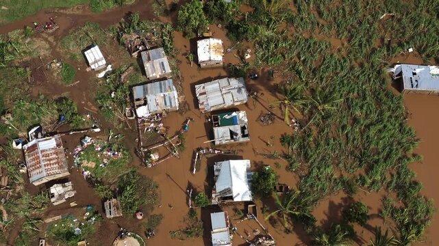 Aerial view of buildings submerged in muddy floodwaters, with debris scattered among the inundated structures and vegetation, Beira, Sofala Province, Mozambique.