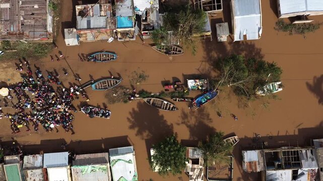 Aerial view of flooded buildings, boats, and people standing in muddy water, illustrating the impact of a natural disaster, Beira, Sofala Province, Mozambique.