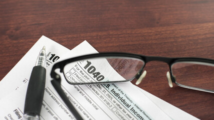 Documents on a table with glasses as a person prepares to fill out their income tax return