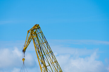 Industrial crane arm against blue cloudy sky.