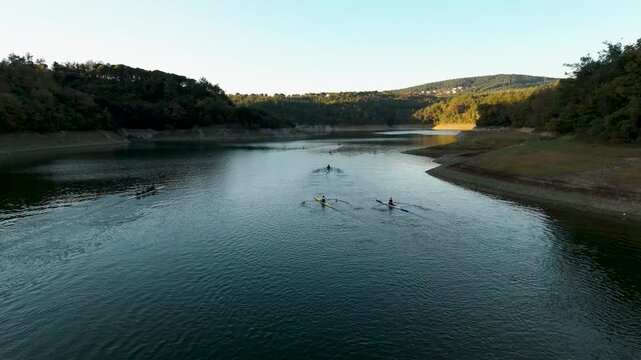 Scenic drone capture of rowing boats on a calm lake surface with hills in the background during a quiet evening training session.