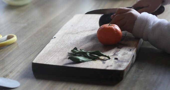 A child first tries to cut a plum with the blunt side of a knife, then gets impatient and turns it over to cut properly. A real-life learning moment.