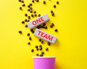 One Team symbol. Concept word One Team on wooden blocks. Beautiful yellow background with coffee cup. Business and One Team concept. Copy space