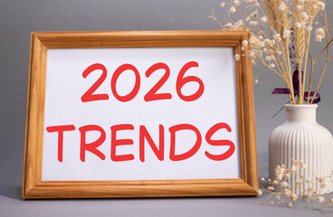 2026 Trends symbol. Concept words 2026 Trends on beautiful wooden picture frame. Beautiful grey background with flower vase. Business and 2026 Trends concept. Copy space.