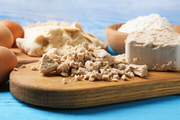 Compressed yeast, eggs, dough and flour on light blue wooden table, closeup