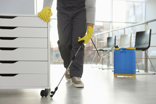 Pest control worker spraying insecticide indoors, closeup
