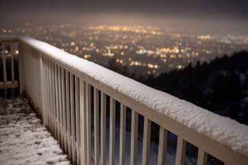 Snowy railing overlook deck city lights night winter frost bokeh hillside calm view with quiet mood over glowing urban landscape