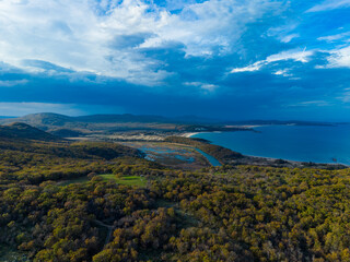 Scenic view of landscape with hills and water under cloudy sky in the late afternoon at a coastal area