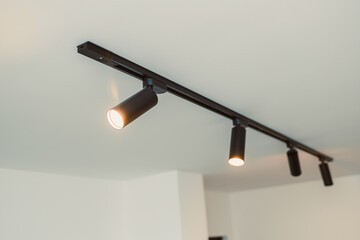 Track lighting with adjustable spots in a modern space showing warm light illuminating the ceiling