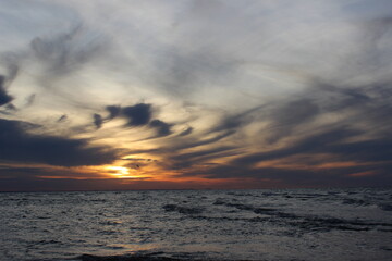 Sunset over the Baltic Sea on the Polish coast, calm sea and dramatic sky during golden hour.