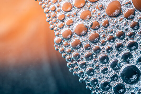 Macro photography of dense bubbles on a dual-tone teal and orange background, creating a cinematic and high-contrast abstract liquid art.
