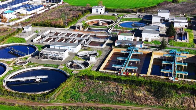 Circular and rectangular tanks in green landscape with surrounding infrastructure and vegetation. Aerial view.