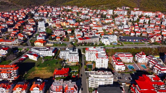 Aerial view of a modern residential district in a resort town. Apartment buildings with bright red roofs, courtyards with turquoise swimming pools, and organized parking lots.