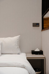 Cozy bedroom corner with white linens and bedside essentials, simple design.