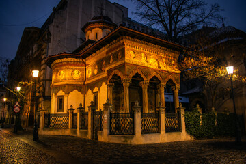 Obraz premium Illuminated historic Orthodox church at night in Old Town Bucharest, Romania. Stavropoleos Church in Cultural Heritage Center, Travel Concept, Tourism 