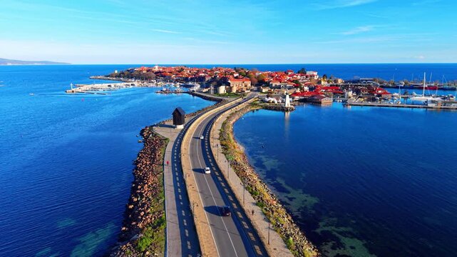 Wide aerial view of a highway bridge connecting the mainland to the historic Nessebar peninsula surrounded by blue water.