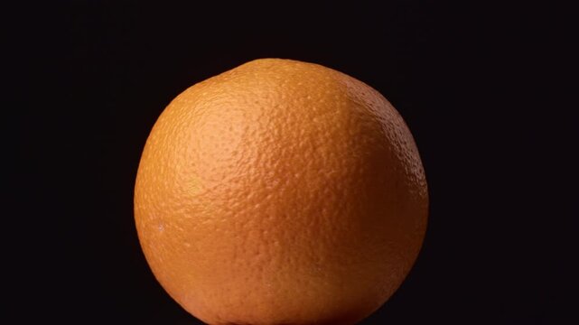 Rotating citrus orange on black background.