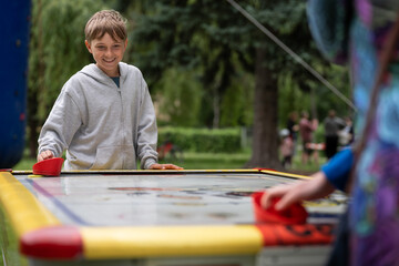 A teenager playing air hockey with a woman (his mother) in the park