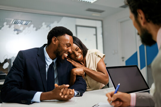 Happy couple laughing with consultant during a business meeting - Powered by Adobe